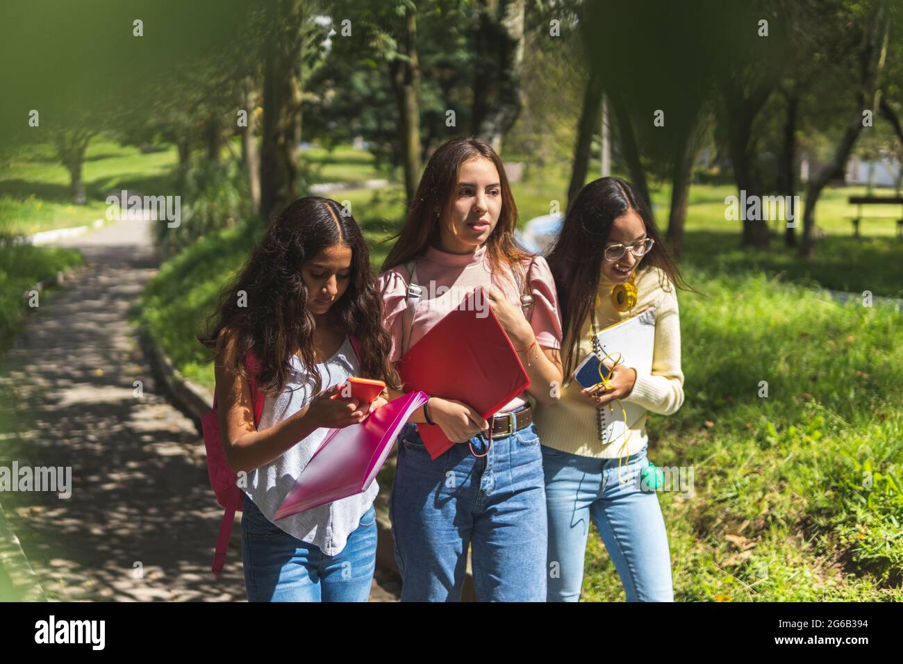 Three teenage girls walking with their notebooks, backpacks and cell phone back to school Stock Photo
