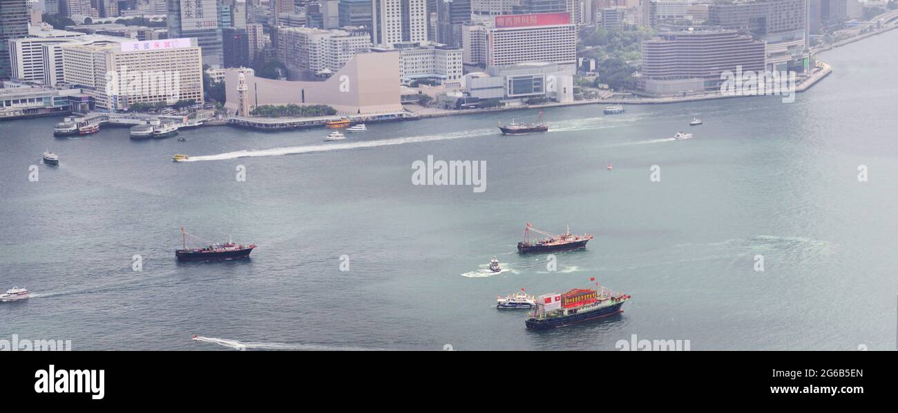 A row of boats carrying the Chinese & Hong Kong flags sail through Victoria harbour on July 1st - HK Special Administrative Region Establishment Day. Stock Photo