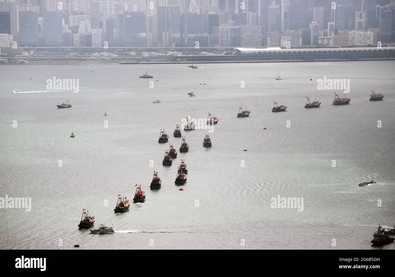 A row of boats carrying the Chinese & Hong Kong flags sail through Victoria harbour on July 1st - HK Special Administrative Region Establishment Day. Stock Photo