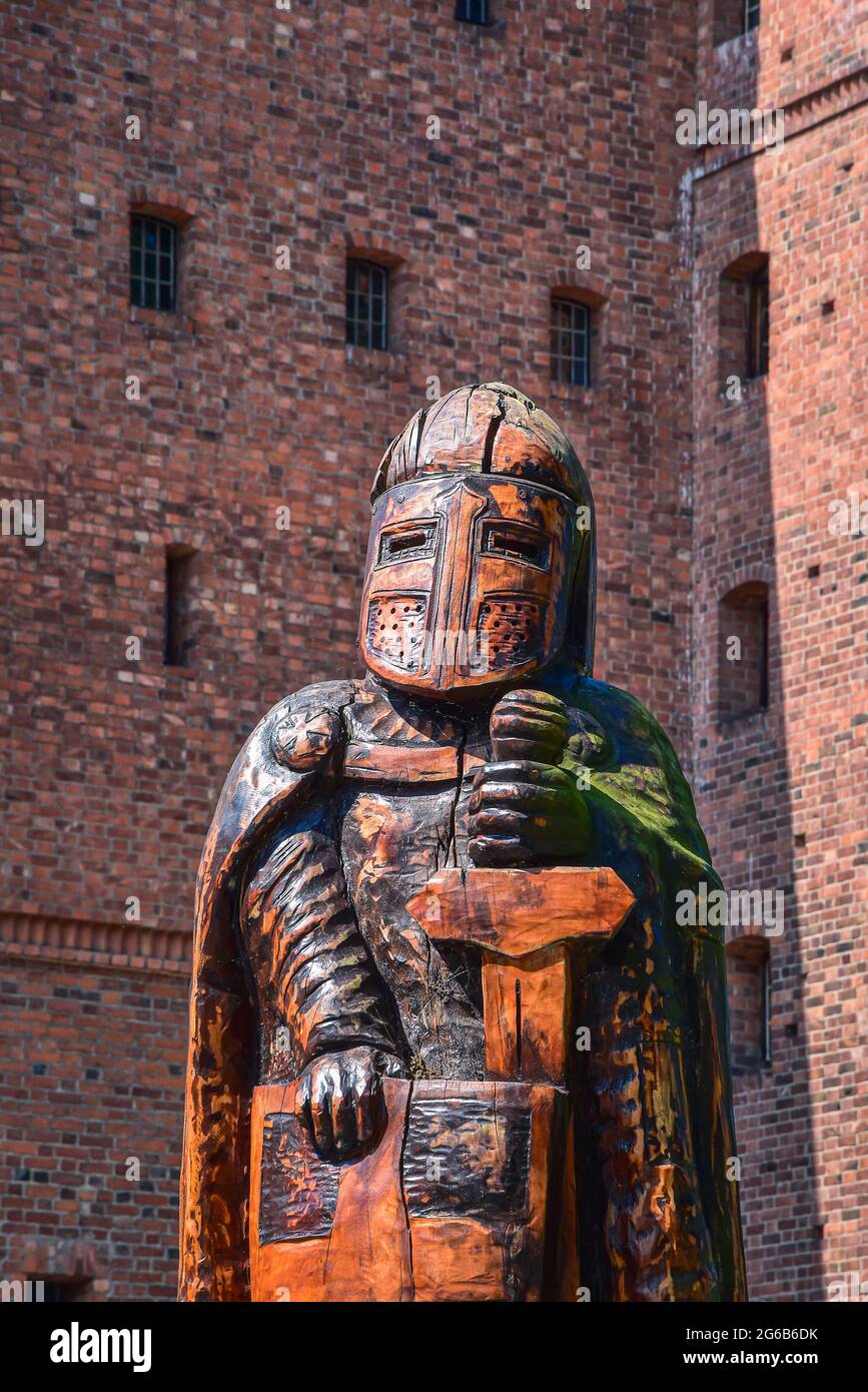 Wooden knight sculpture against brick wall of teutonic medieval castle from XIV and XV century Stock Photo