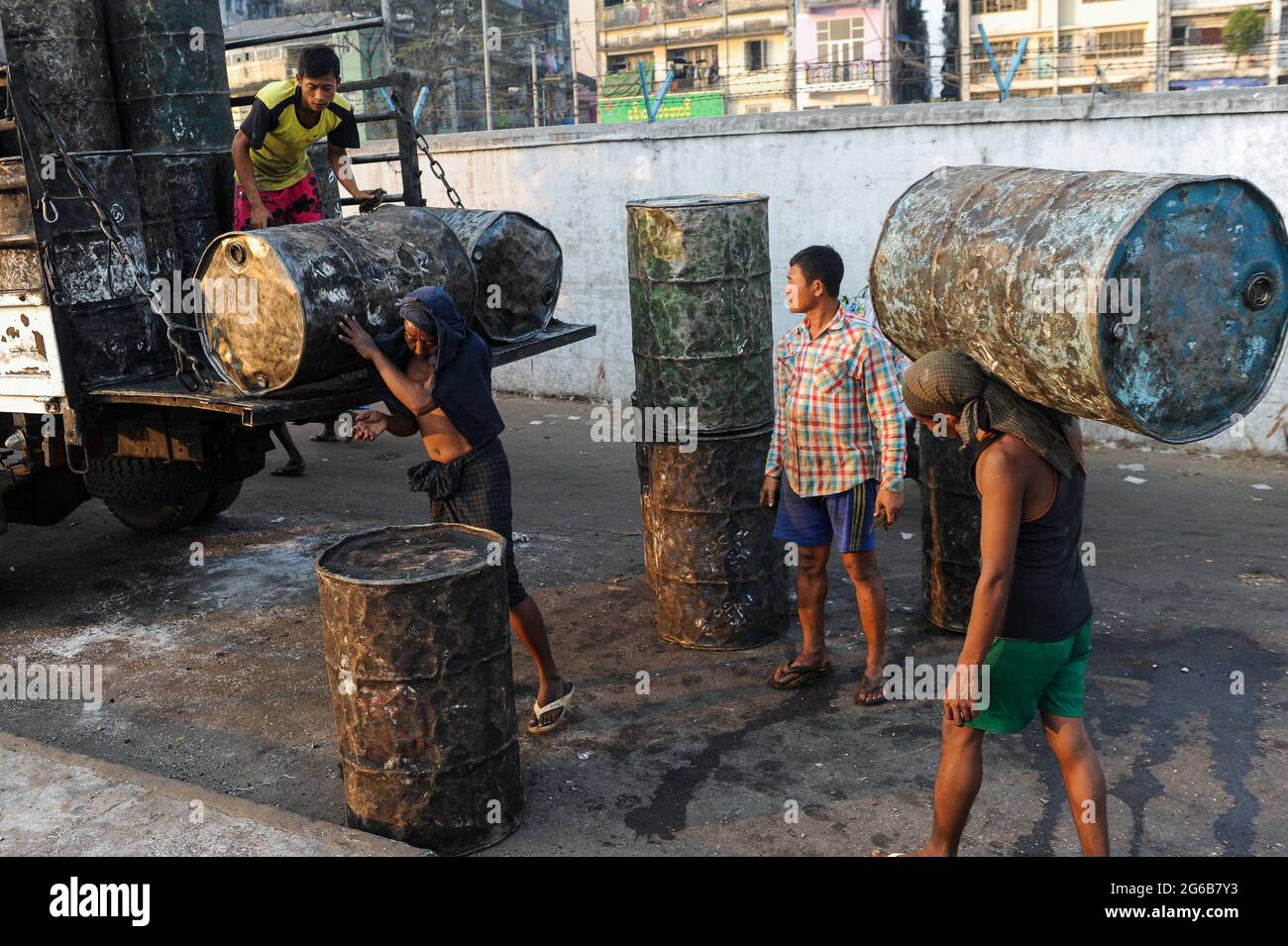 30.01.2014, Yangon, Myanmar, Asia - Workers load empty, rusty oil barrels onto a truck at the harbour along the Yangon River. Stock Photo