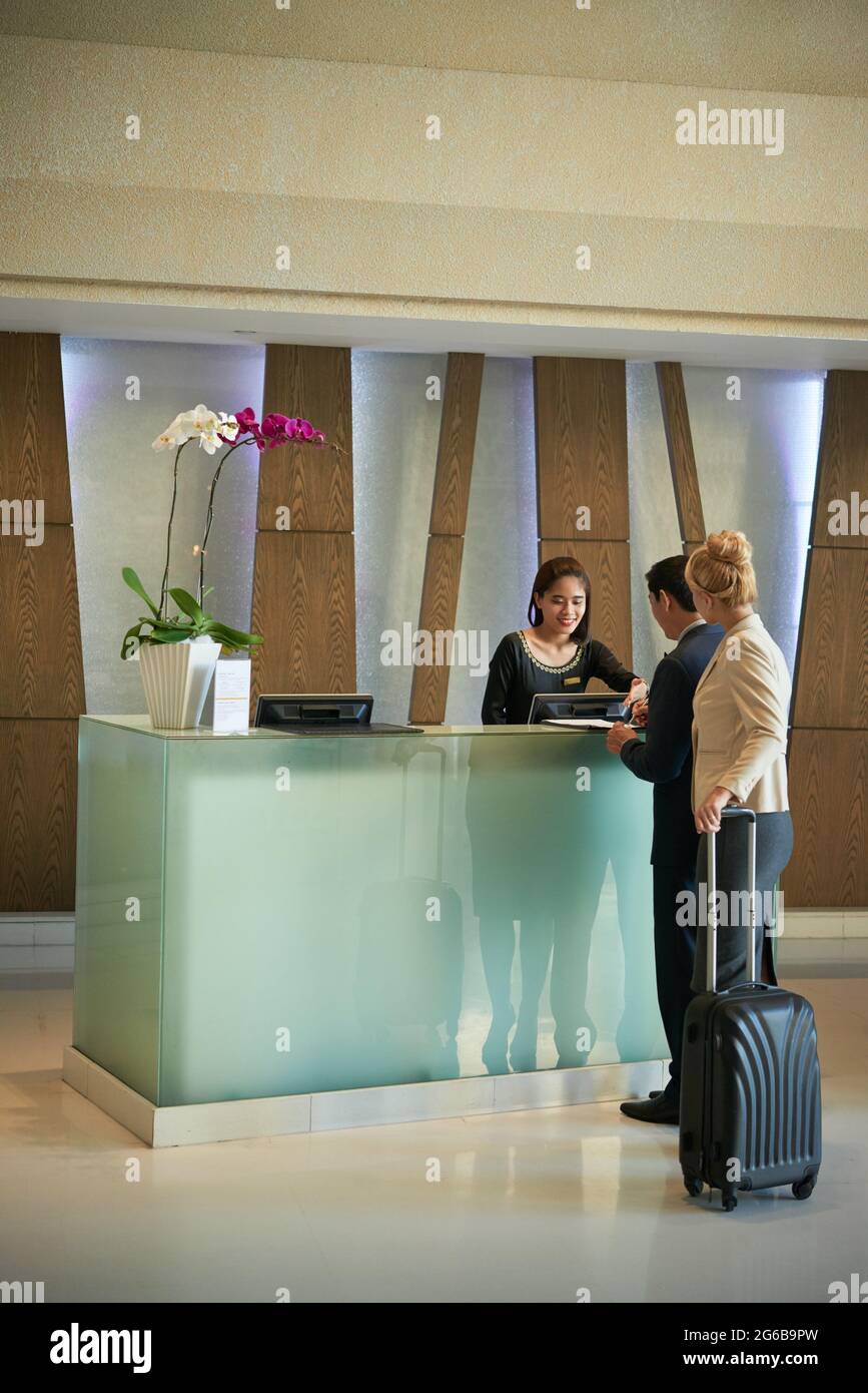 Business people standing in queue at hotel reception, smiling