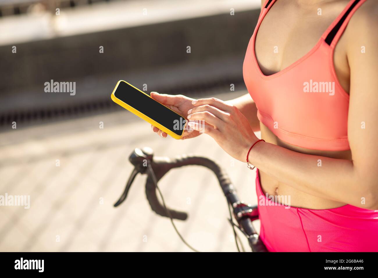 Close up of a girl in sportswear with a smartphone in hands Stock Photo