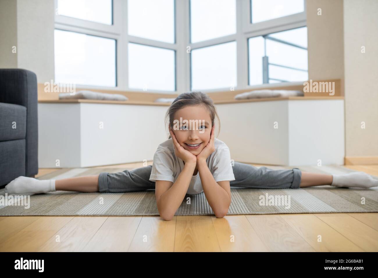 Cute girl sitting on the floor and stretching Stock Photo - Alamy