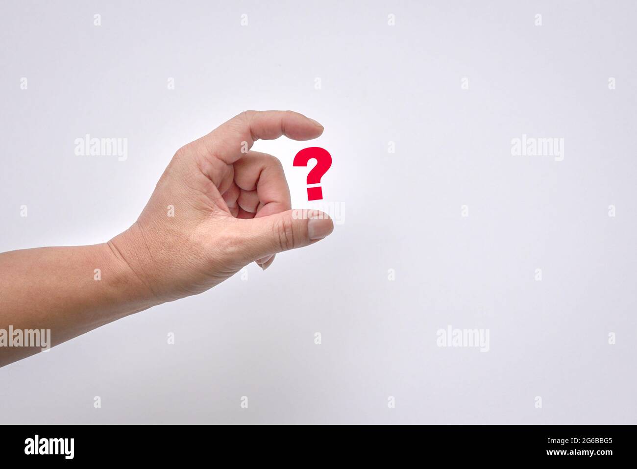 Man's fingers virtually hold a red question mark on white background. Copy space. Stock Photo
