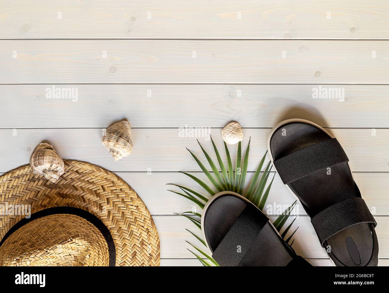 Women's open-toe black sandals from recycled plastic fibers, straw hat, and seashells  Stock Photo