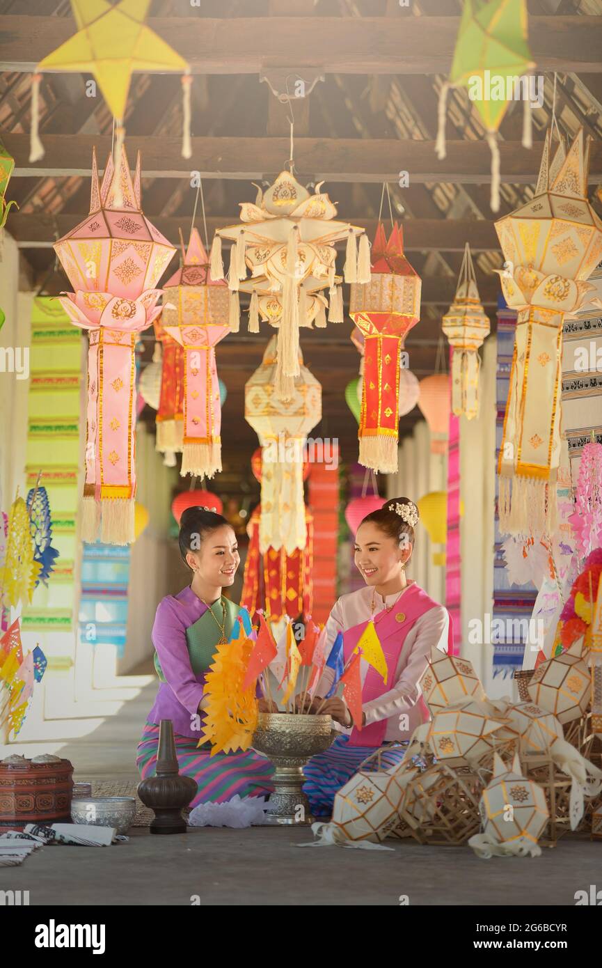 Portrait of two women in traditional Thai clothing sitting amongst lanterns, Thailand Stock Photo