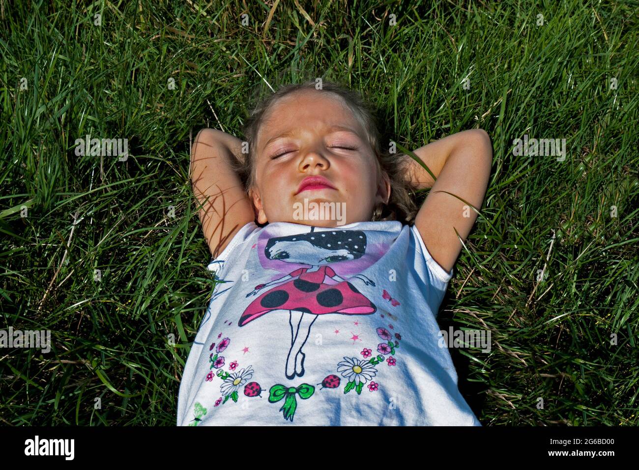 Overhead view of a girl lying in a meadow in the summer sun, Poland Stock Photo