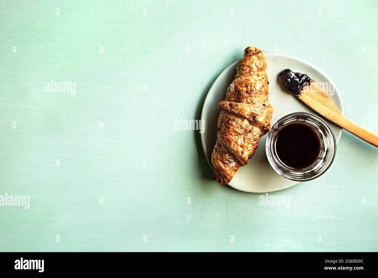 Buttery Croissant with Jam and a glass of Black Coffee Stock Photo