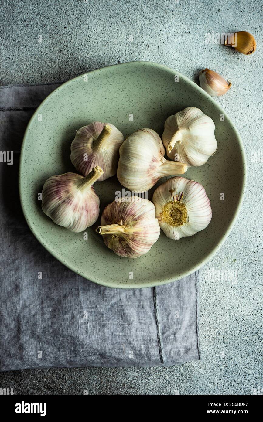 Bowl of fresh cloves of garlic and garlic bulbs on a table Stock Photo ...