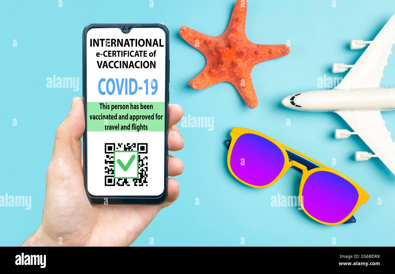 Coronavirus vaccination certificate or vaccine passport for travellers concept. COVID-19 immunity e-passport in the smartphone mobile app for international travelling. Blue background with sunglasses and plane. Stock Photo