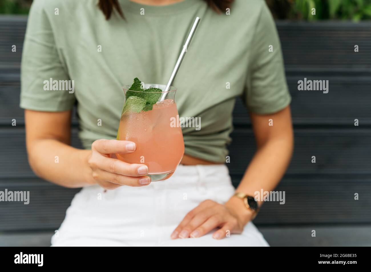 Portrait of a woman with holding a paloma cocktail sitting on a bench Stock Photo