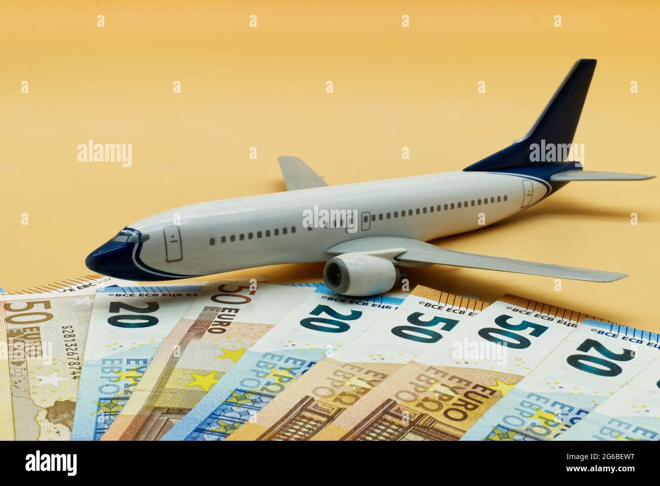 Commercial airplane toy and a pile of Euro banknotes. Flights cost concept Stock Photo