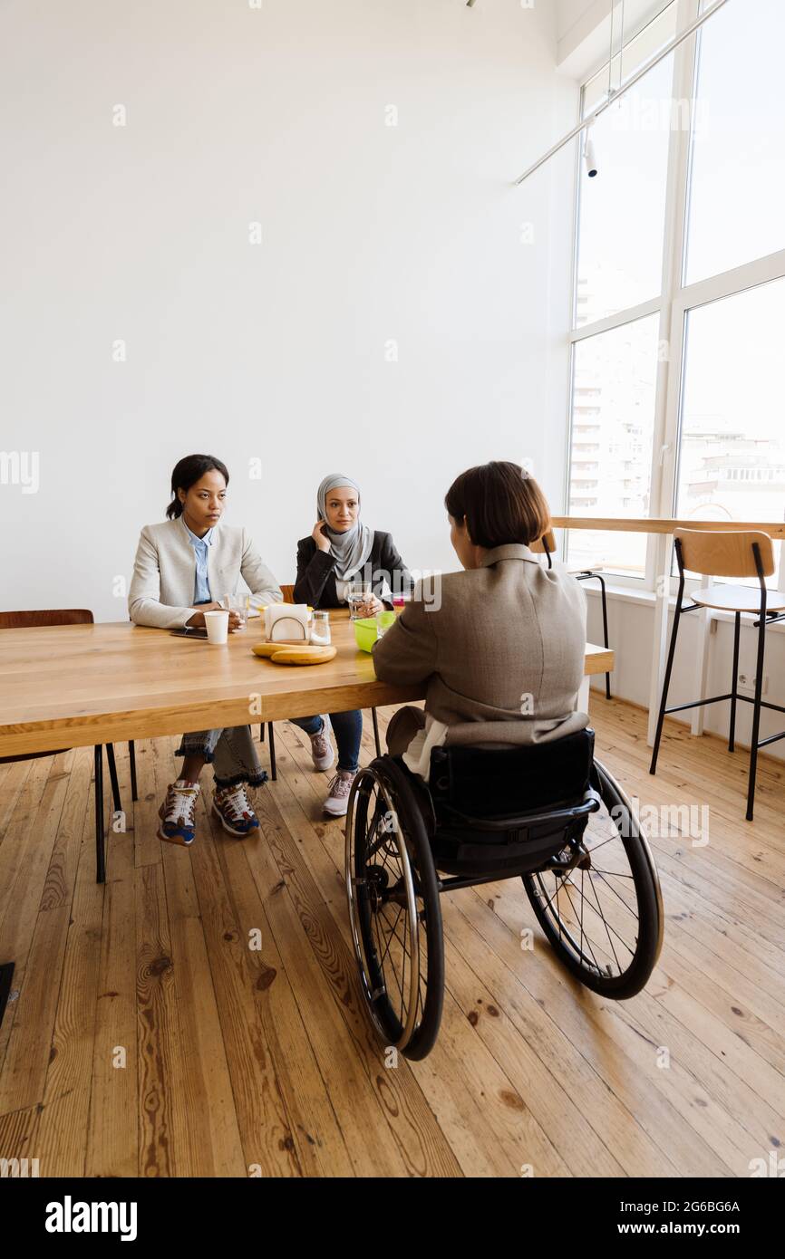 Three multiracial women discussing project while having break in office Stock Photo