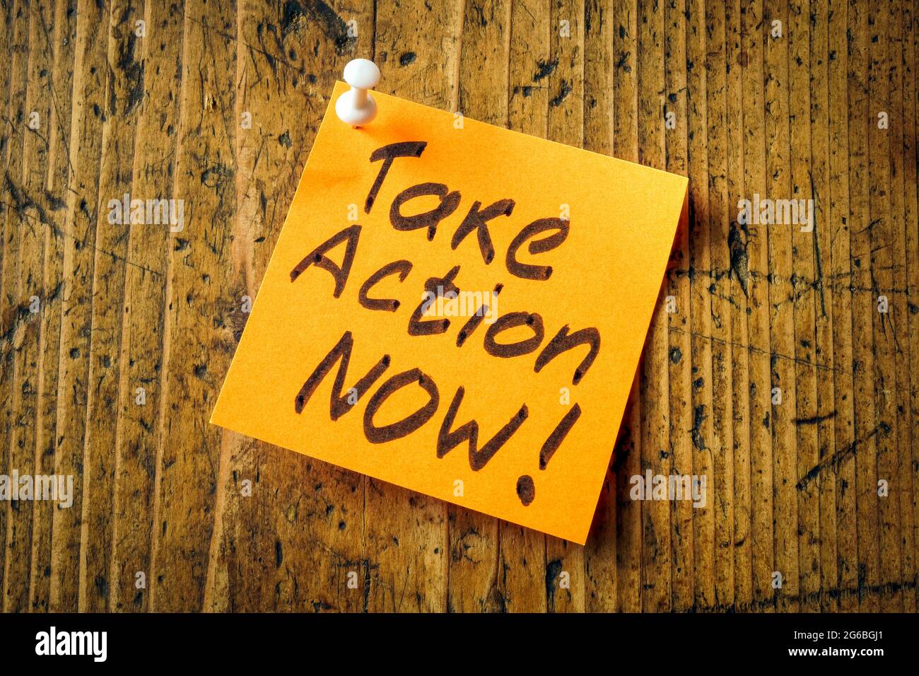 Take action now pinned to desk motivation quote. Stock Photo