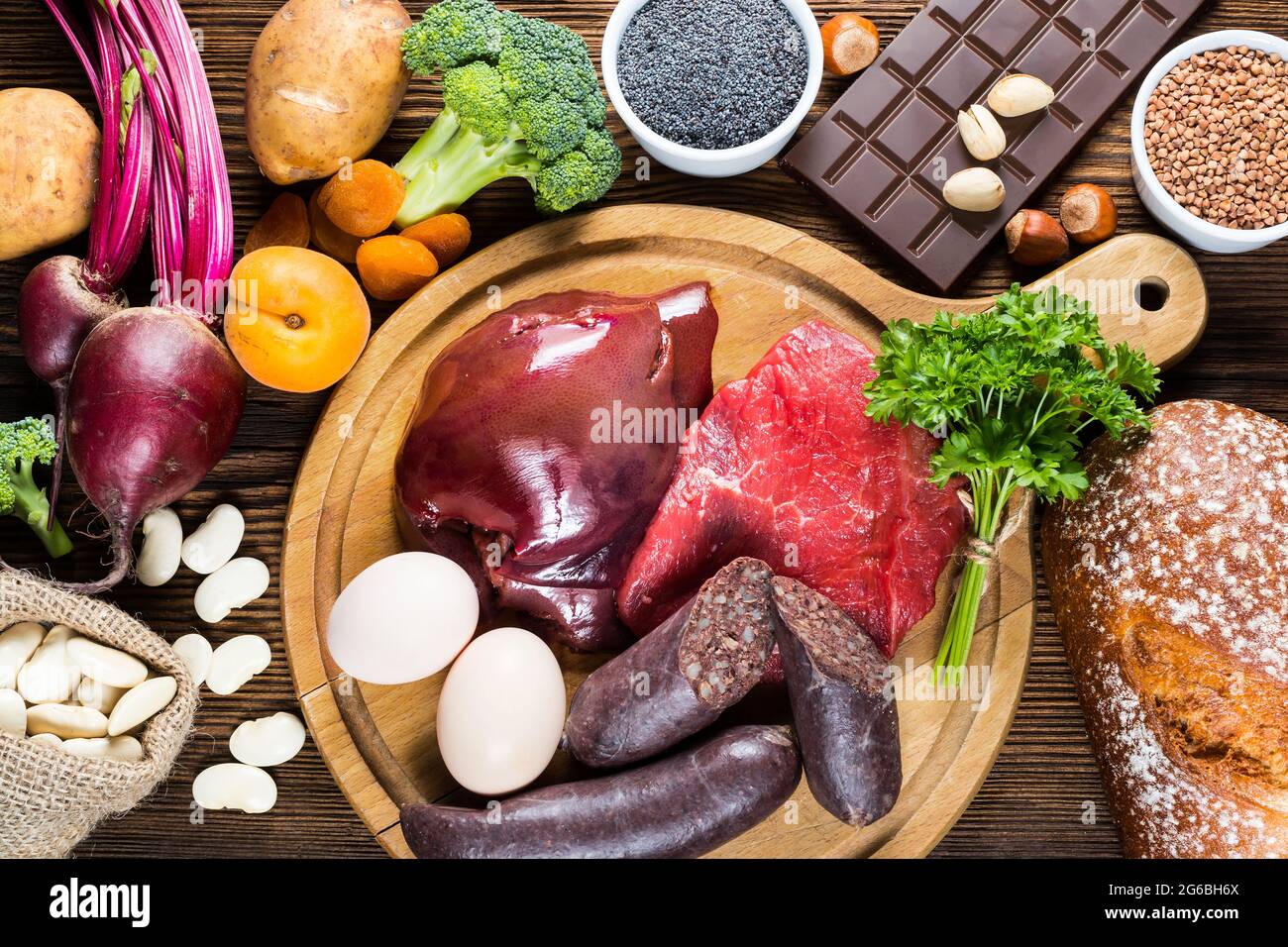 Collection iron rich foods as liver, beef, blood sausage, eggs, rye bread, dark chocolate, parsley leaves, dried apricots, bean, blue poppy seed, broc Stock Photo