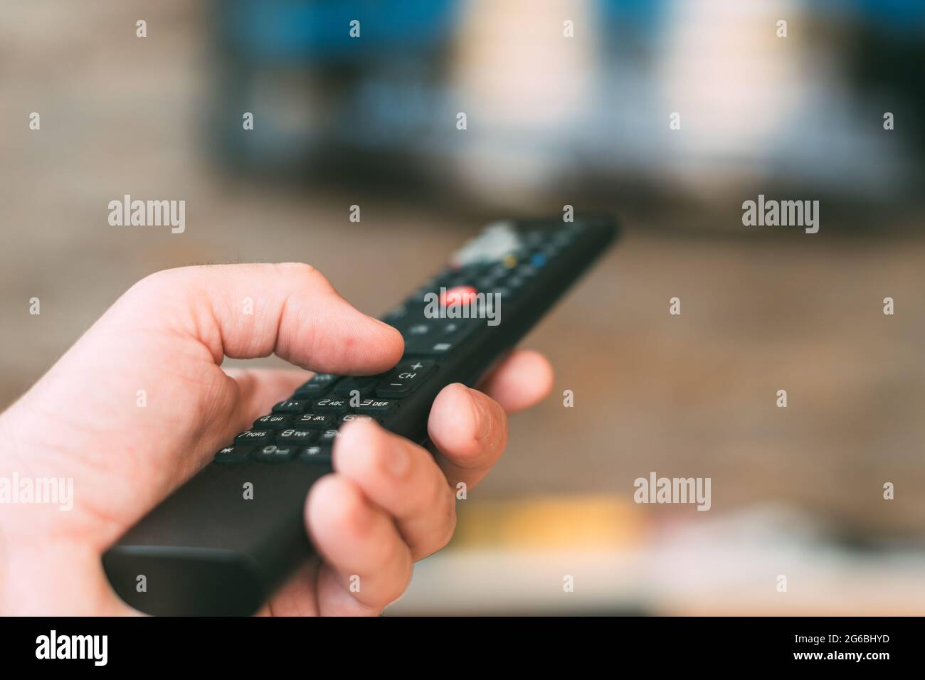 Male hand holding television remote controller, close up with selective focus Stock Photo