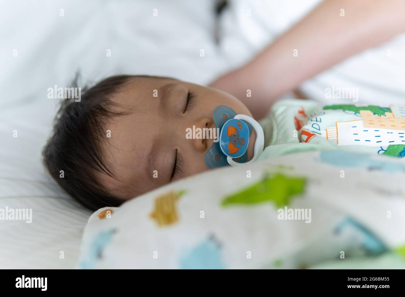 Little Asia Chinese child sleeping on white bed with sucking pacifier ...
