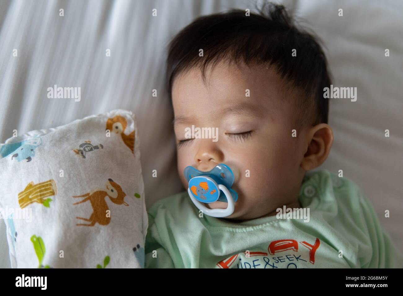 Little Asia Chinese child sleeping on white bed with sucking pacifier ...