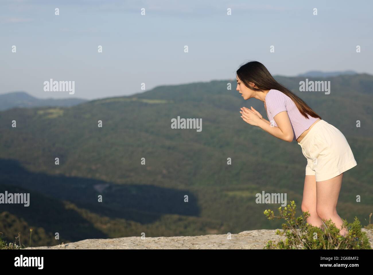 Scared asian woman suffering vertigo looking down on a mountain cliff Stock Photo