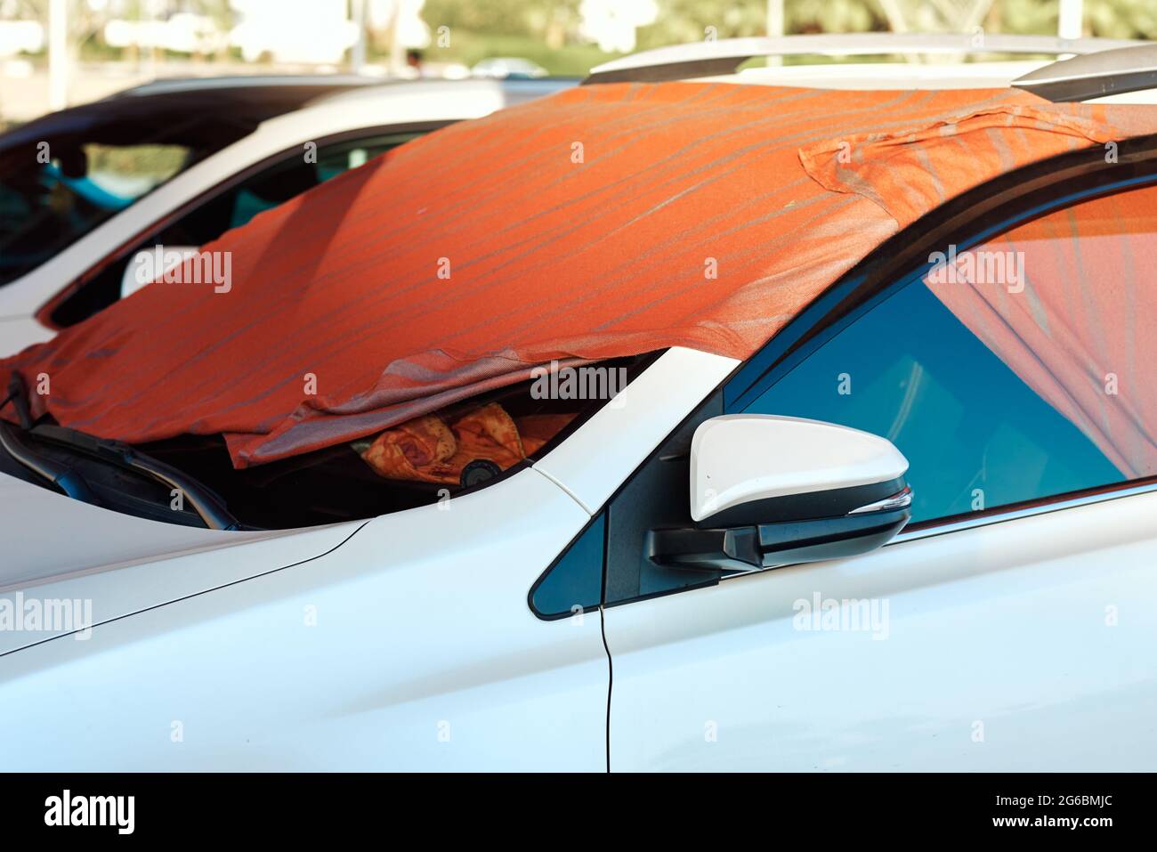 White car windshield covered by sun shade made of blanket in hot