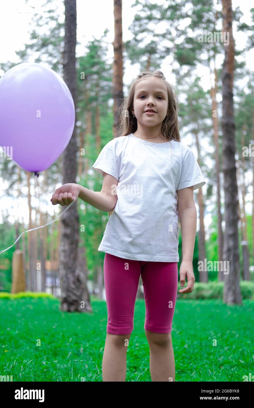 pretty girl in pink leggings and white t shirt with purple hot air balloon in park. holliday party birthday celebration. happy children Stock Photo Alamy