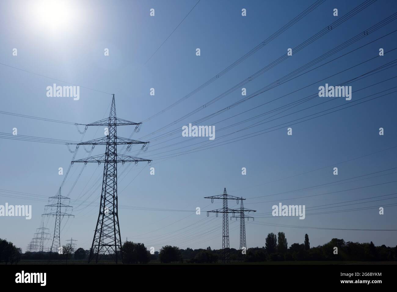 Electricity pylons against a clear blue sky on a sunny day Stock Photo