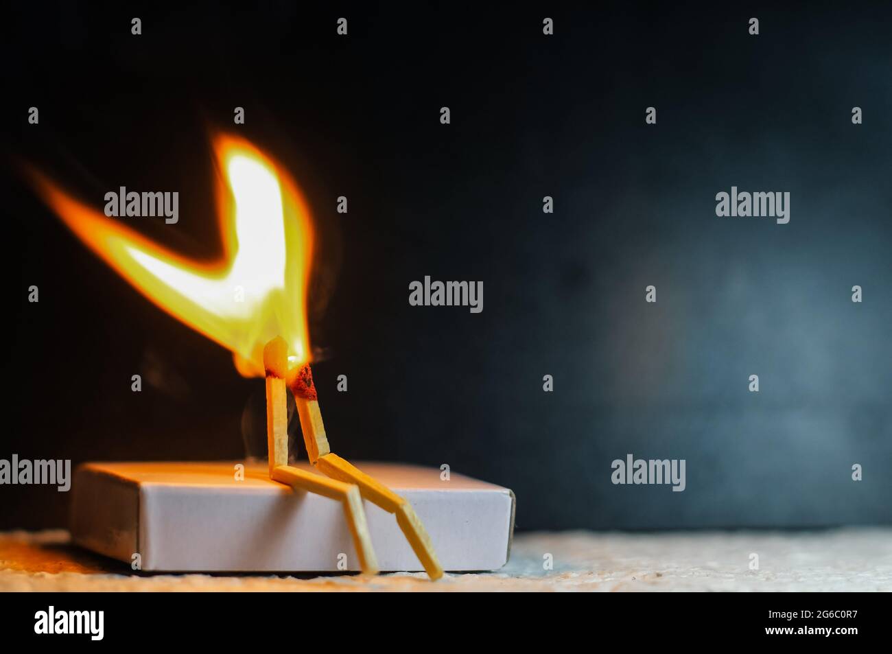 Two matches burning sitting together on the matchbox in the dark copy space. Two matches in