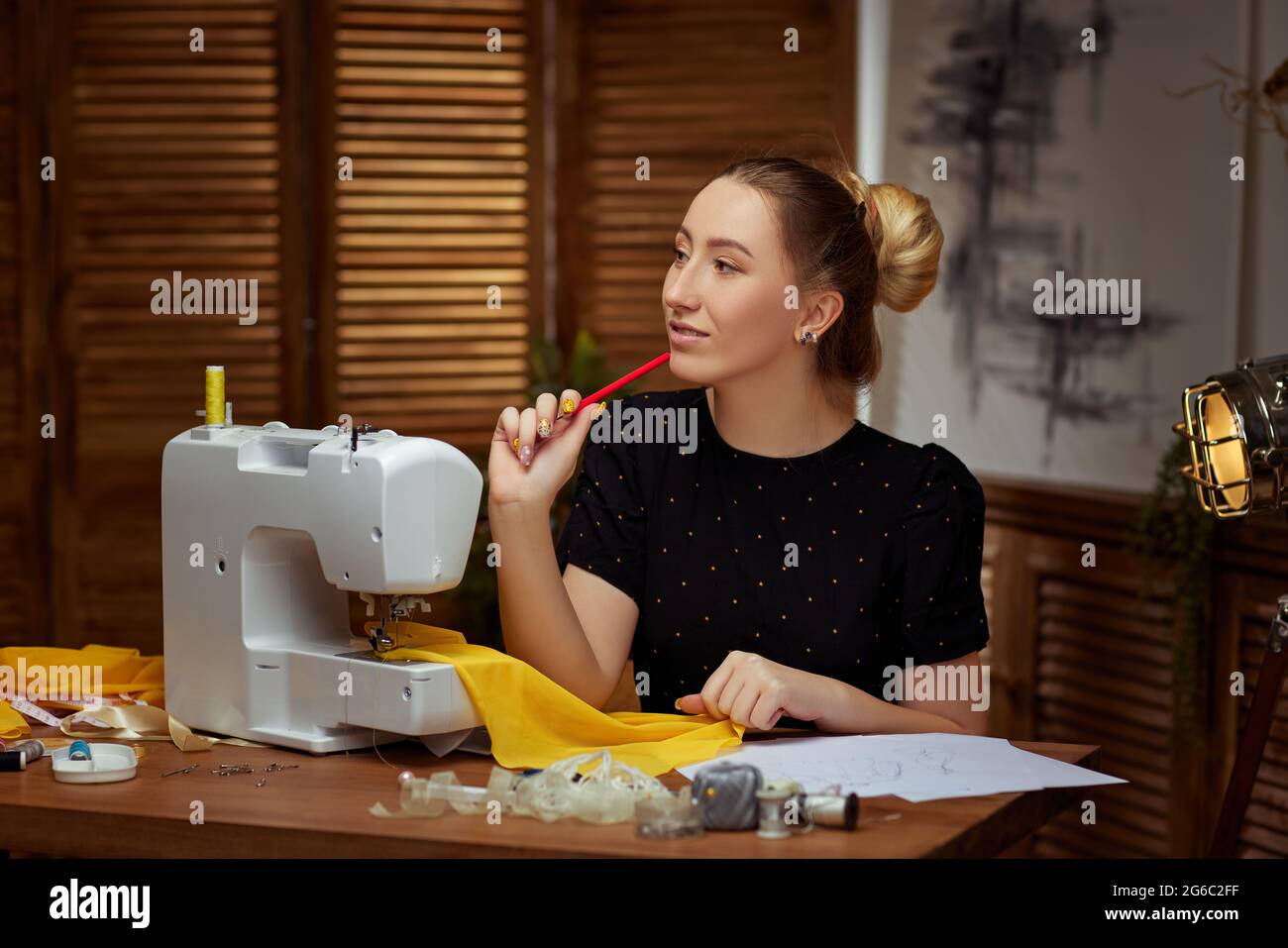 Beautiful young seamstress working on sewing machine Stock Photo