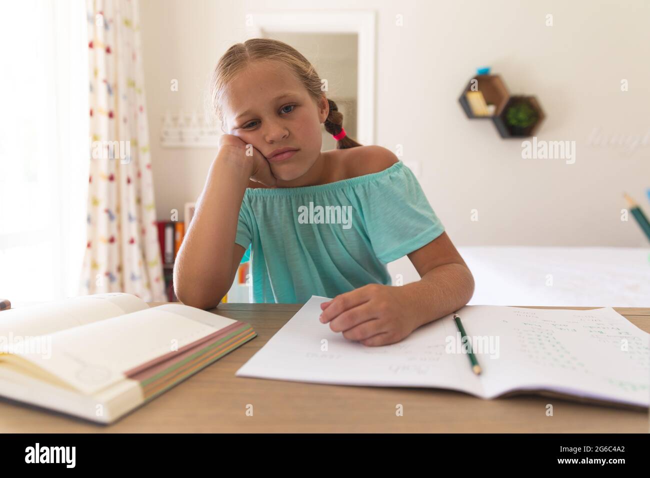 Bored caucasian girl having video call during class, sitting at desk at home Stock Photo
