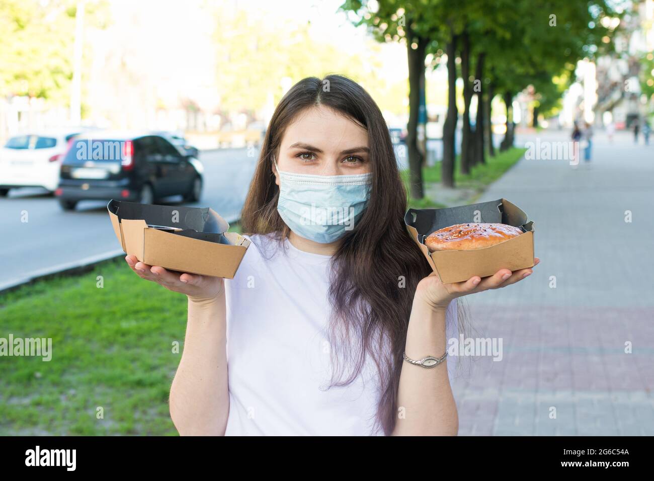 A masked woman deliverer of food during a pandemic and quarantine keeps ...
