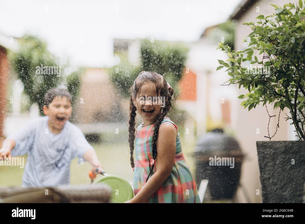 Summer games with water hose in the garden. Stock Photo