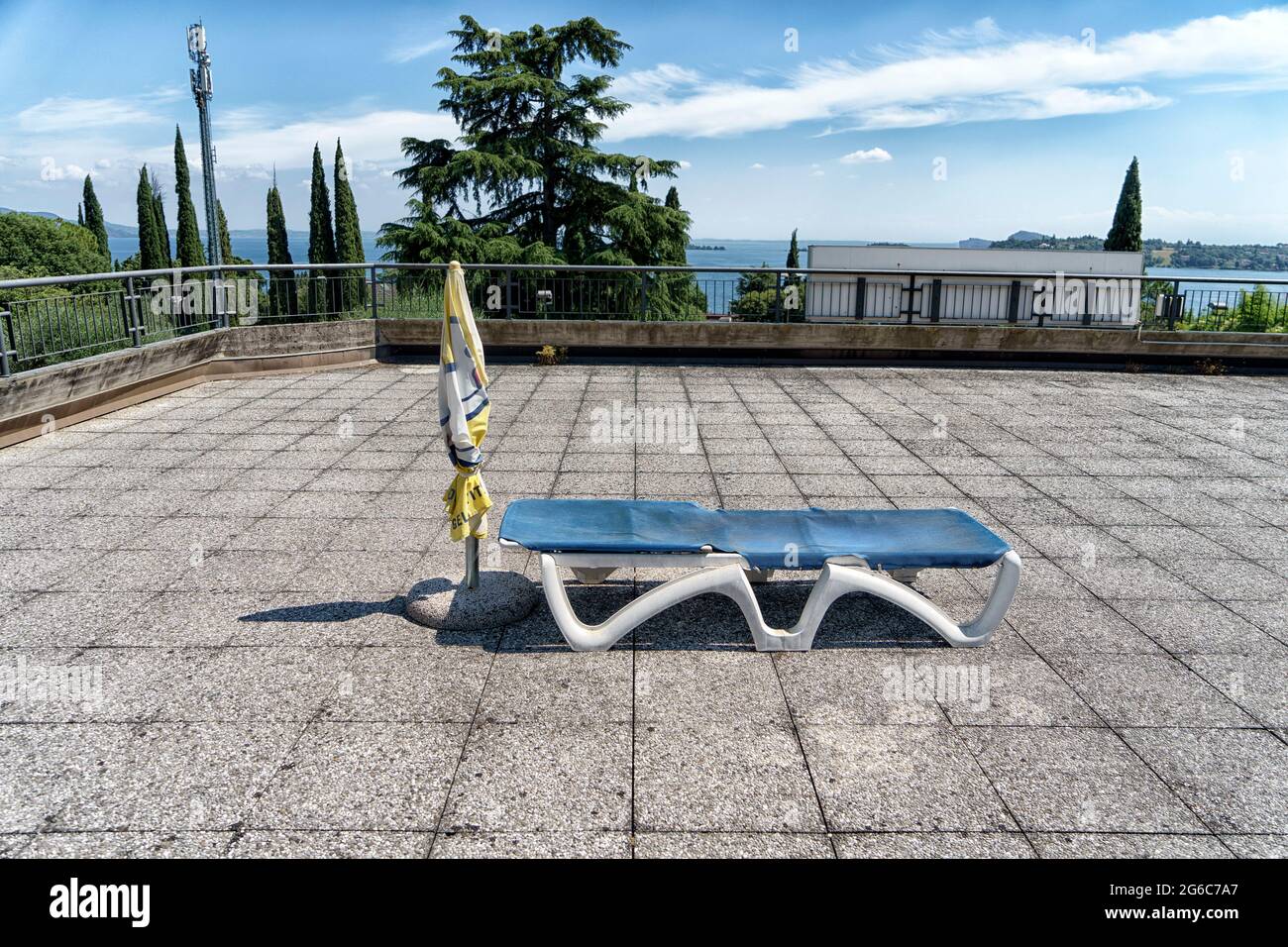 Abandoned sunlounger an parasol on a rooftop in the city of Gardone Riviera at the shore of Garda Lake in Lombardy, Italy Stock Photo