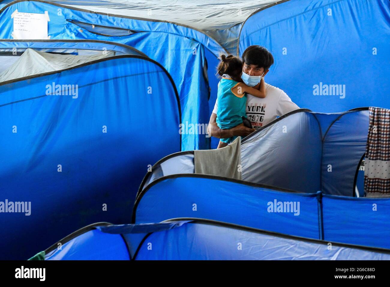 Batangas, Philippines. 5th July, 2021. A man and his daughter take shelter inside an evacuation center as the Taal volcano continues to rumble in Batangas Province, the Philippines, on July 5, 2021. Philippine volcanologists warned that an eruption could occur in Taal volcano, south of Manila, 'anytime soon' after recording the highest levels of sulfur dioxide gas emission on Sunday. Credit: Rouelle Umali/Xinhua/Alamy Live News Stock Photo