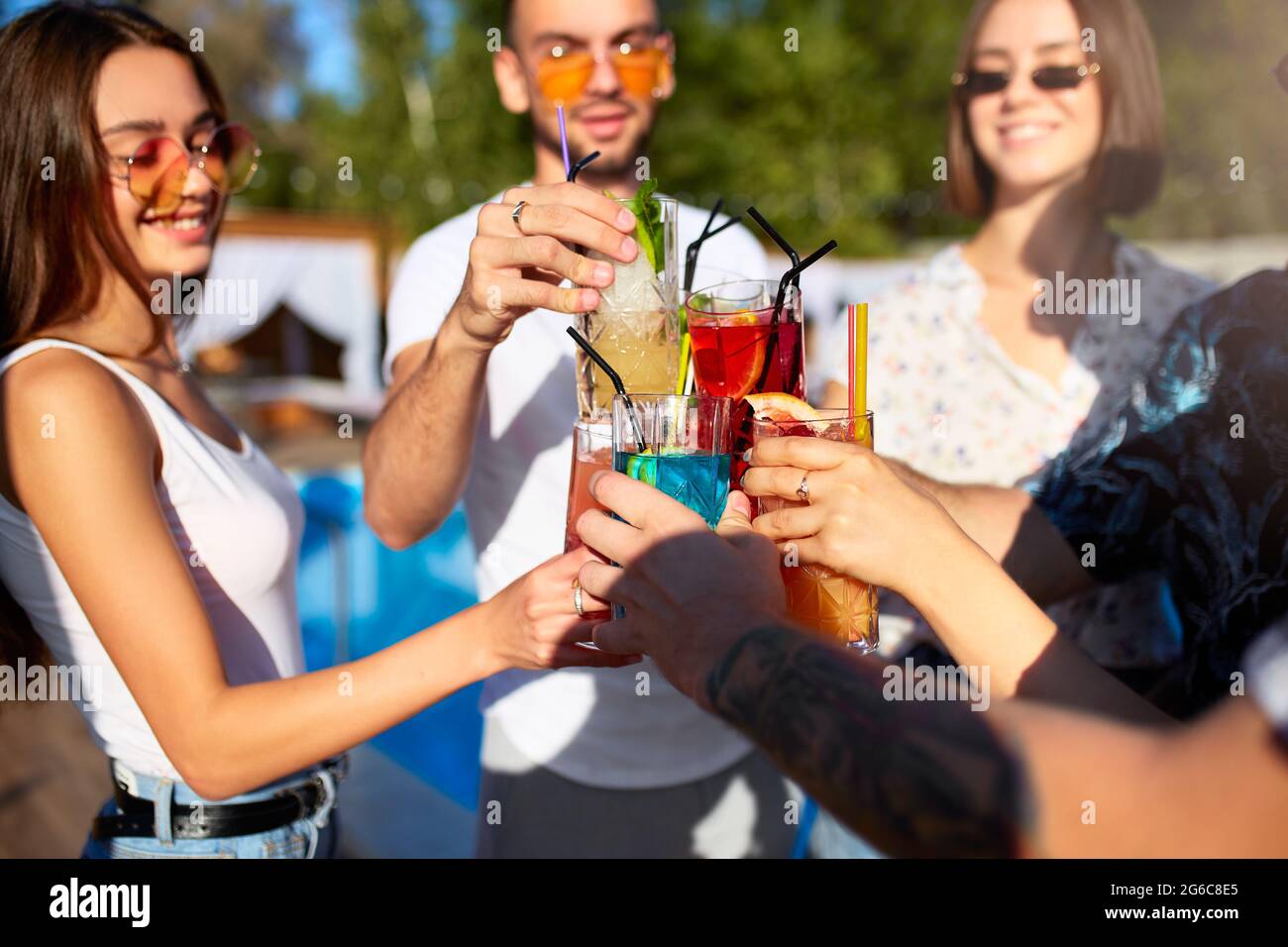 Group Of Friends Having Fun At Poolside Summer Party Clinking Glasses