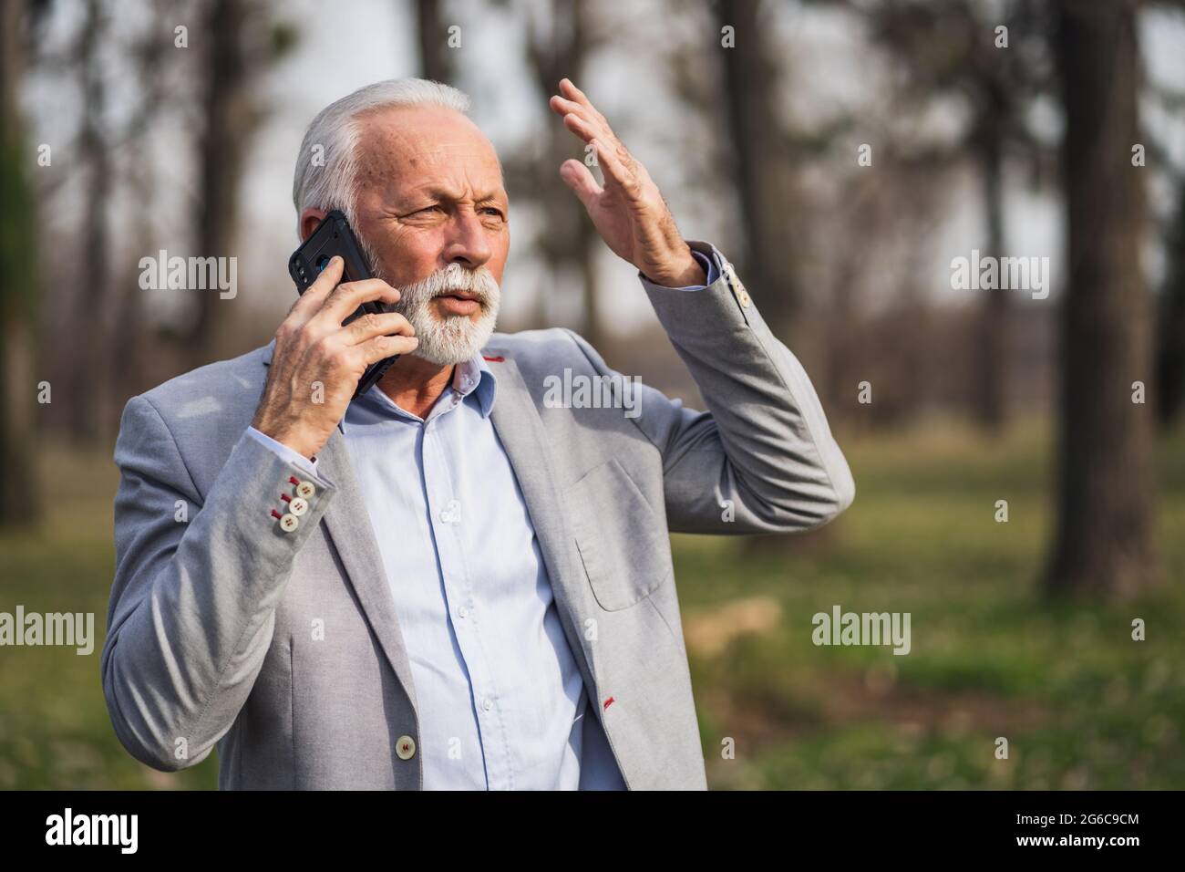 Senior businessman is talking on smartphone. He is upset. Stock Photo