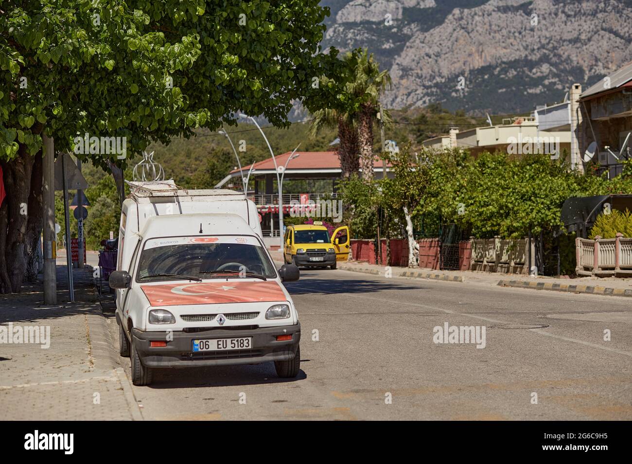 Alanya, Turkey - May 24, 2021: White auto with turkish flag. Yellow taxi on the road on bright sunny day and mountains view. Travel Turkey concept Stock Photo