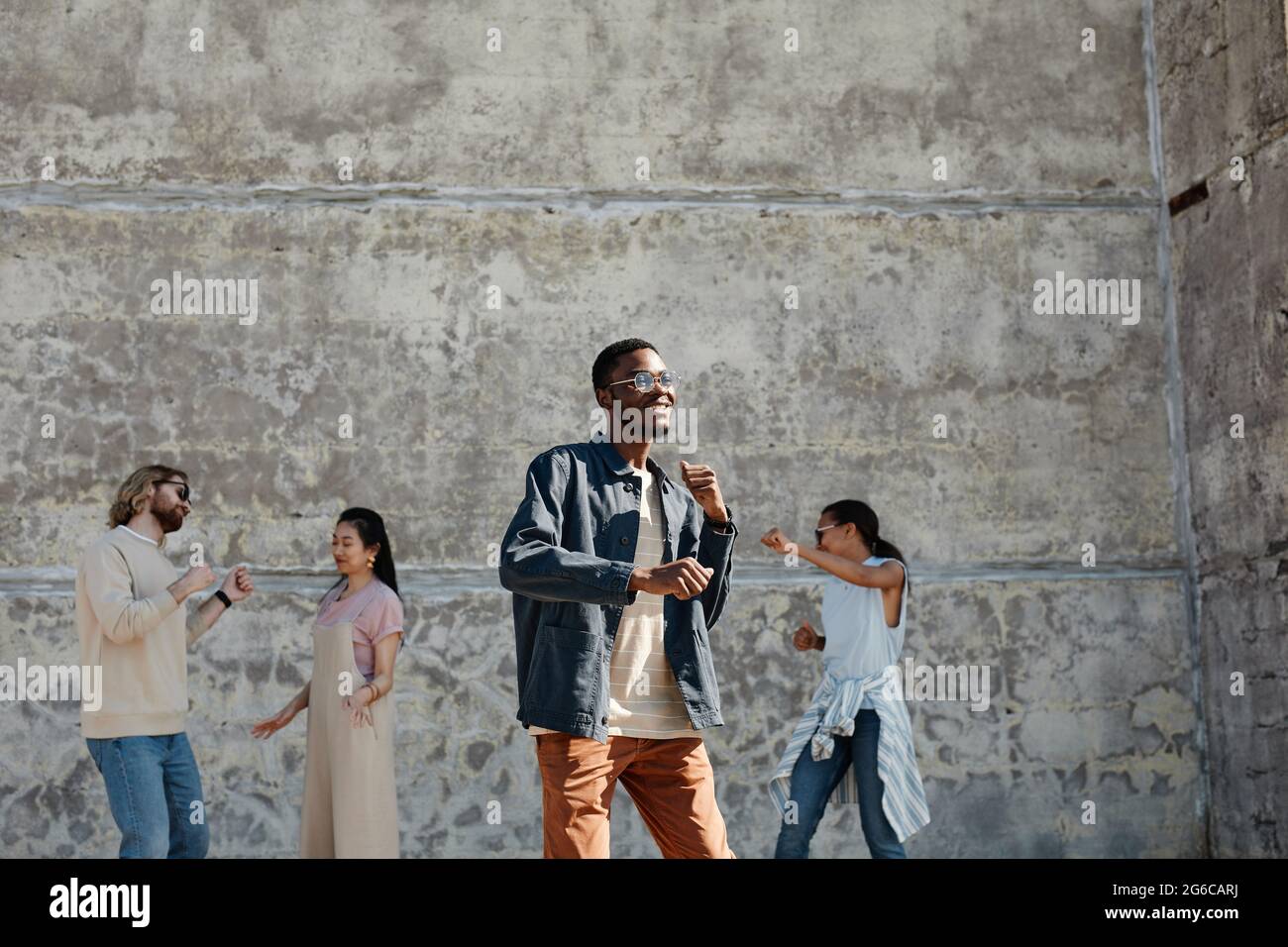 Wide angle view at diverse group of young people dancing outdoors in ...