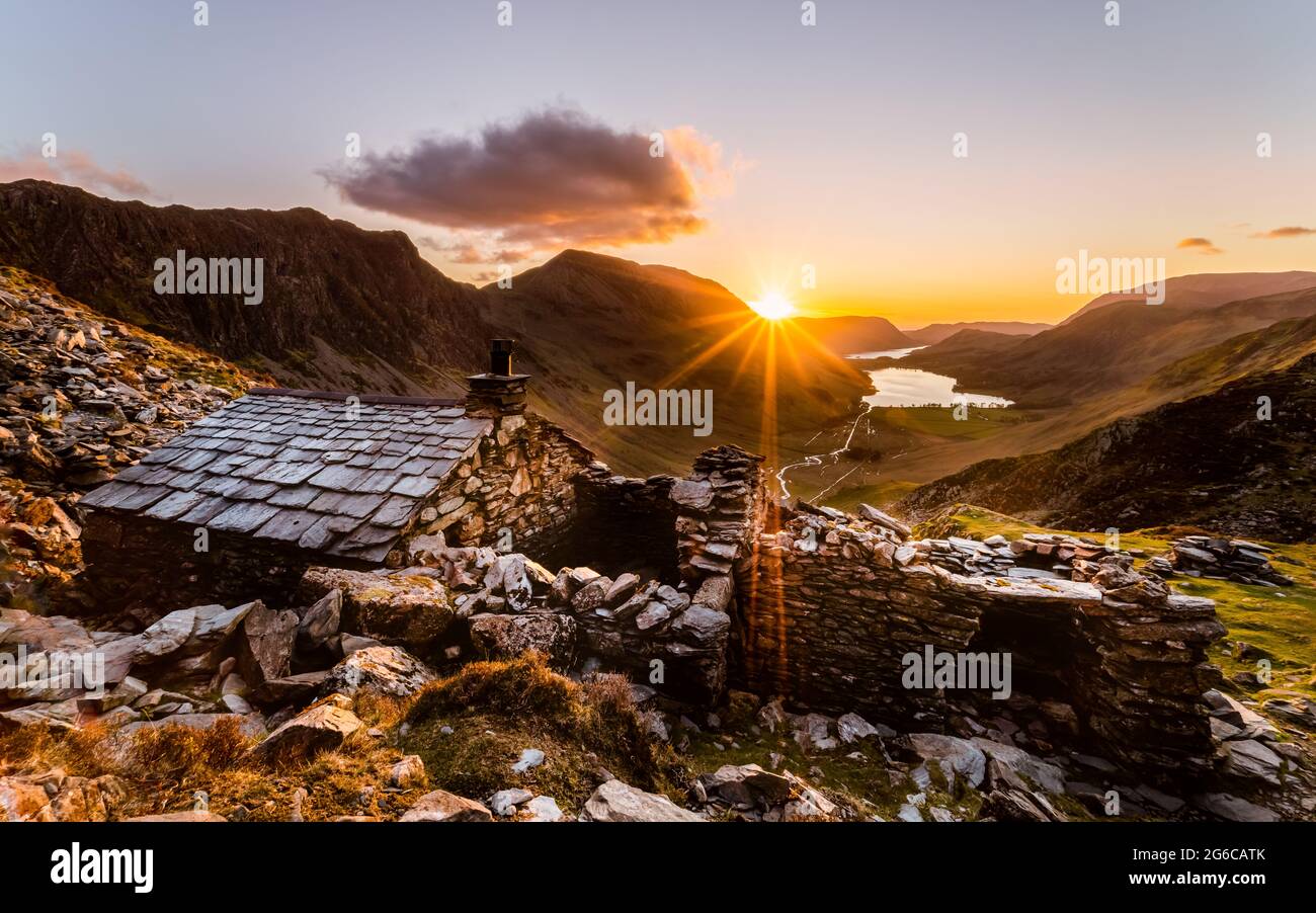 Warnscale Bothy Sunset with a large sunbeam coming through from over the mountain ridge line and looking out towards Buttermere Lake. Stock Photo