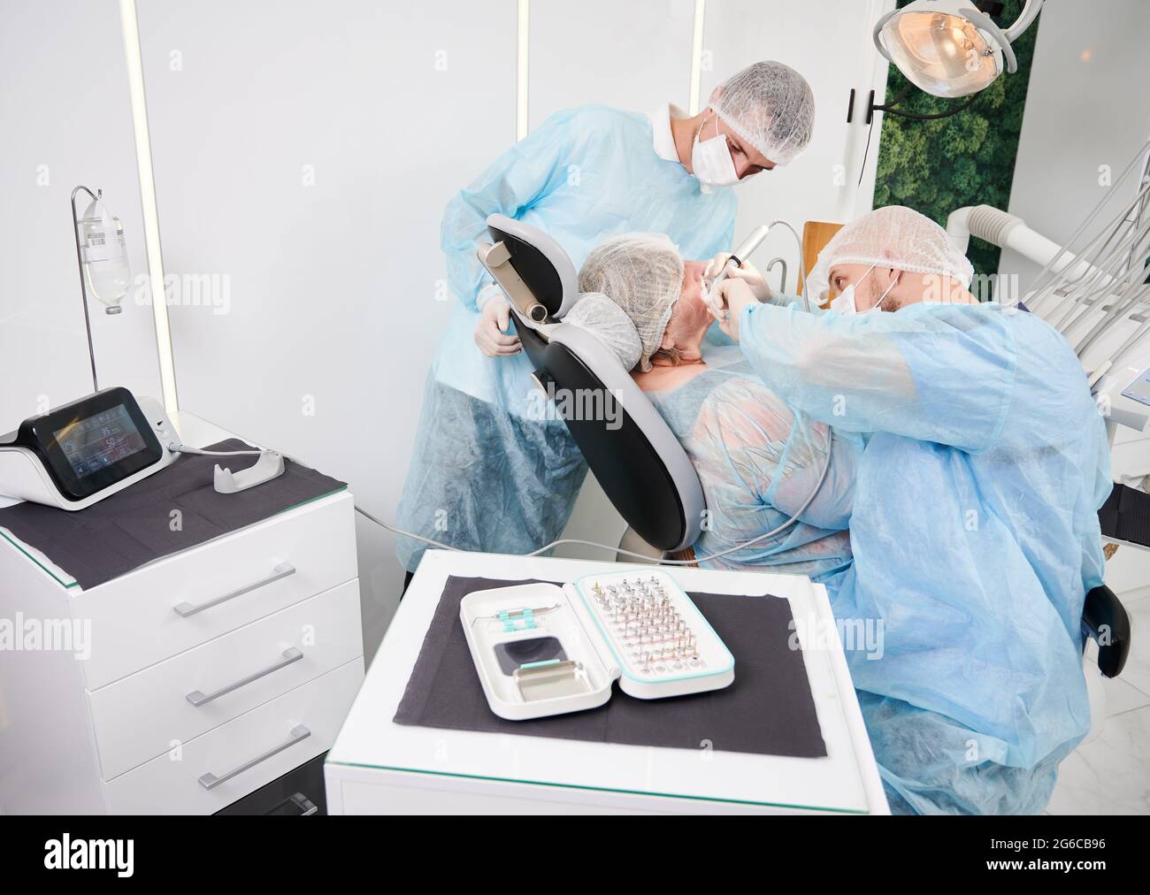 Implantology procedure with implant physiodispenser. Male dentist using