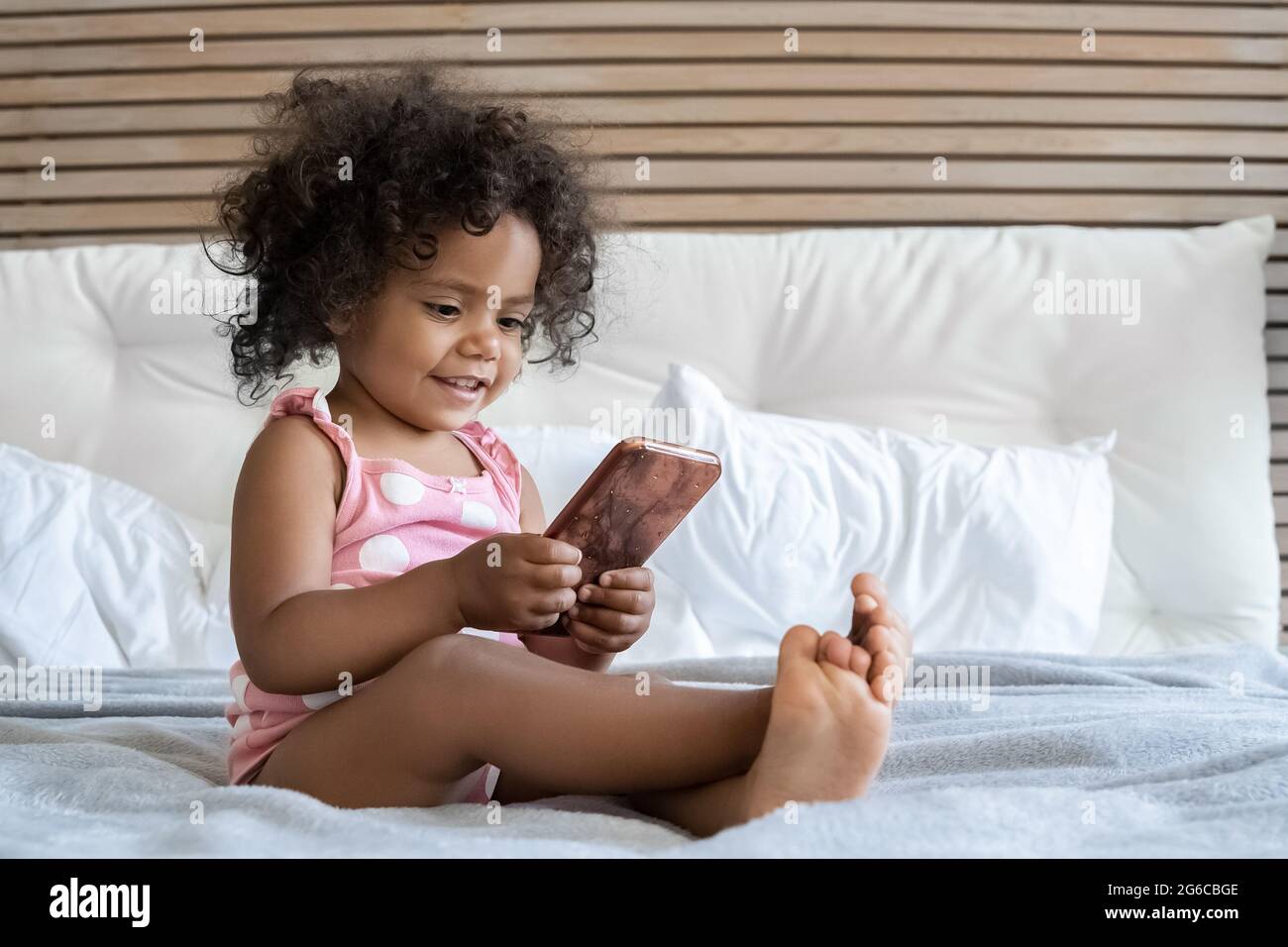 Cute barefoot african american girl little hild playing with mobile phone Stock Photo