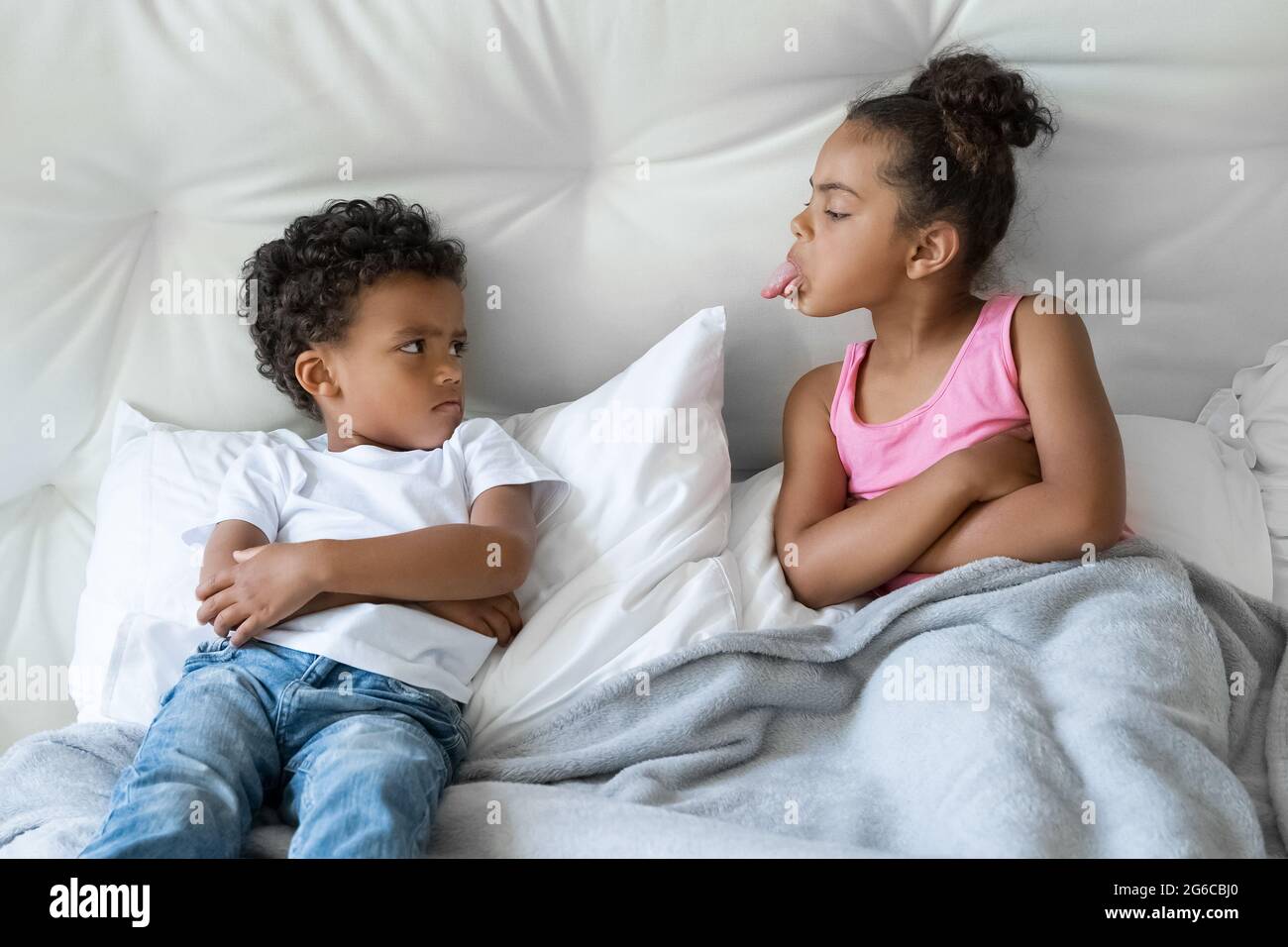 African American sister and brother little children quarreling lying in bed Stock Photo