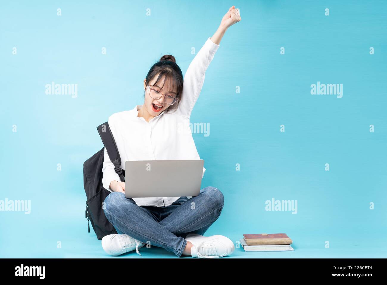 Portrait of a happy young woman sitting on a blue background Stock Photo