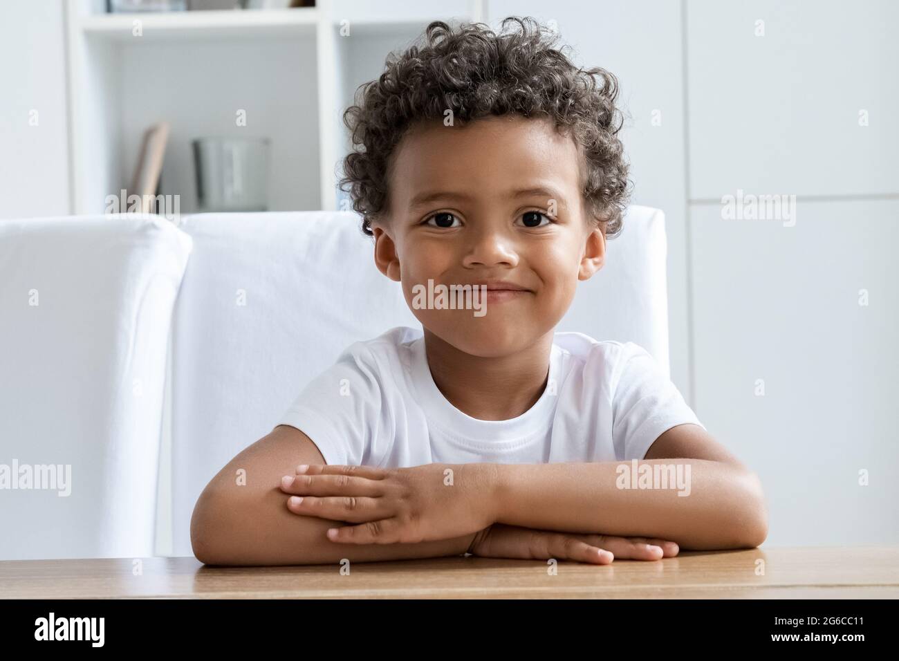 Cute happy smiling preschool boy child student sitting at desk looking at camera Stock Photo