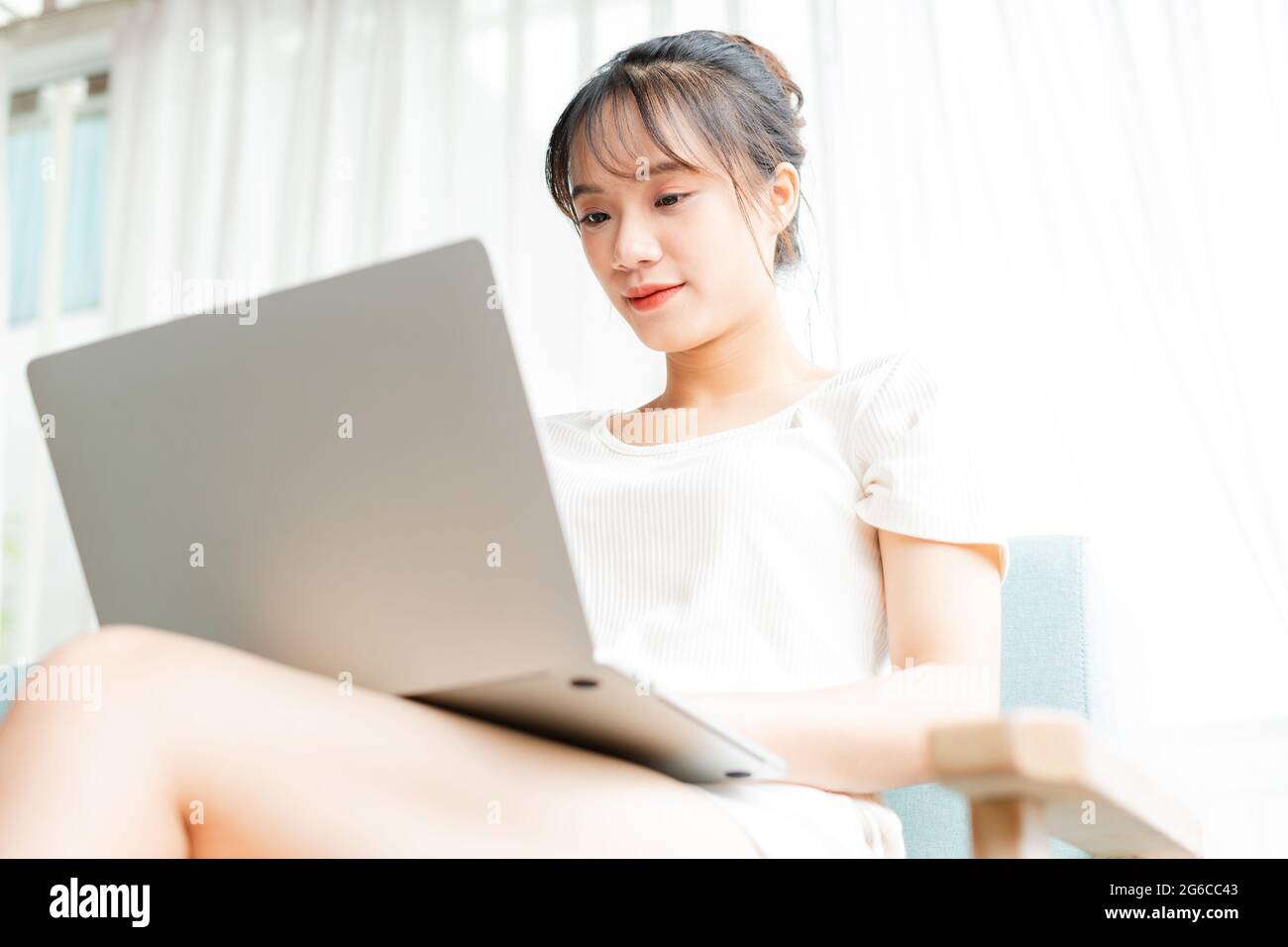 portrait of young girl sitting on sofa at home using laptop Stock Photo ...
