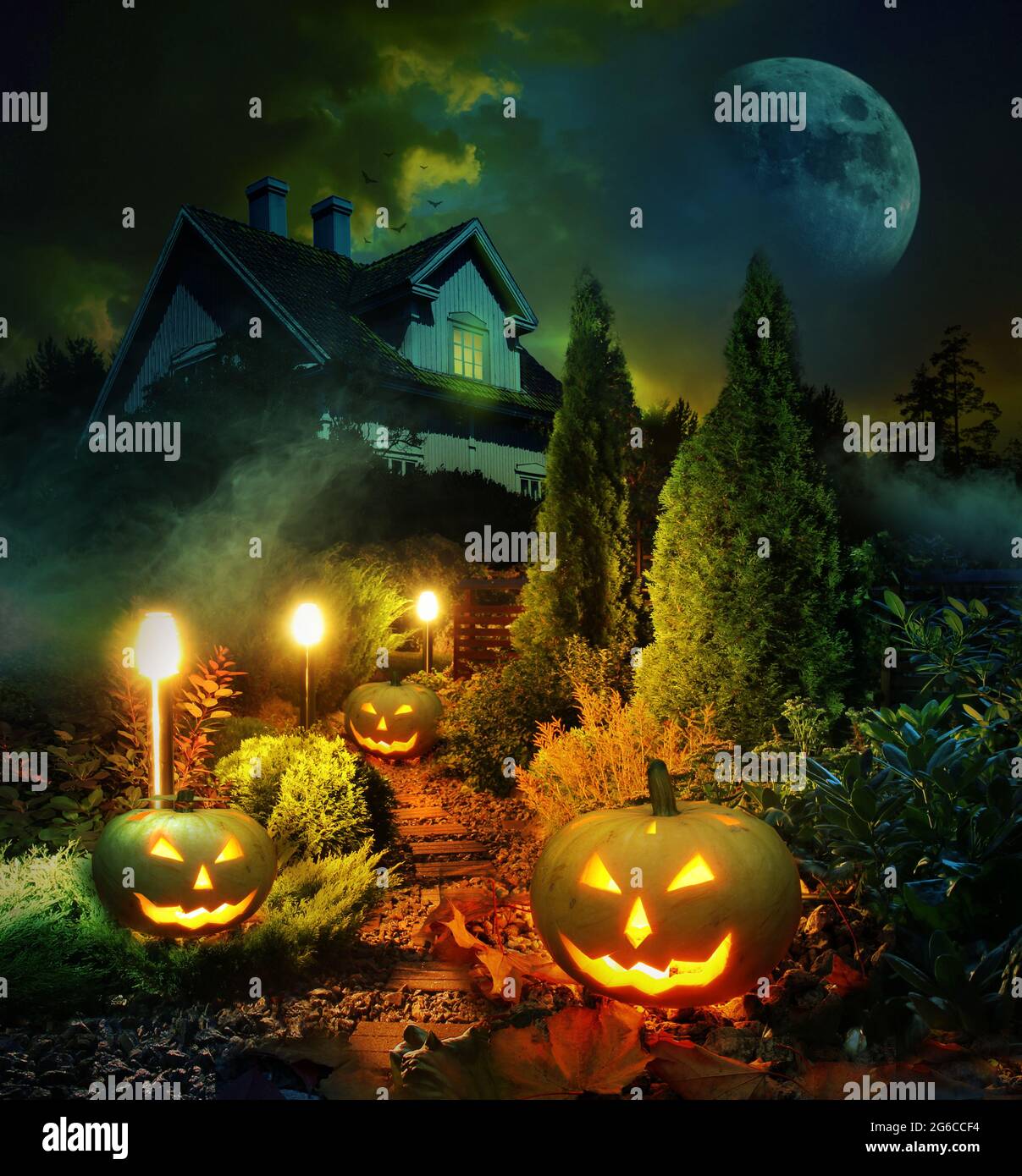 Night scene of Halloween pumpkin lanterns pathway throug mystery garden to scary haunted house Stock Photo
