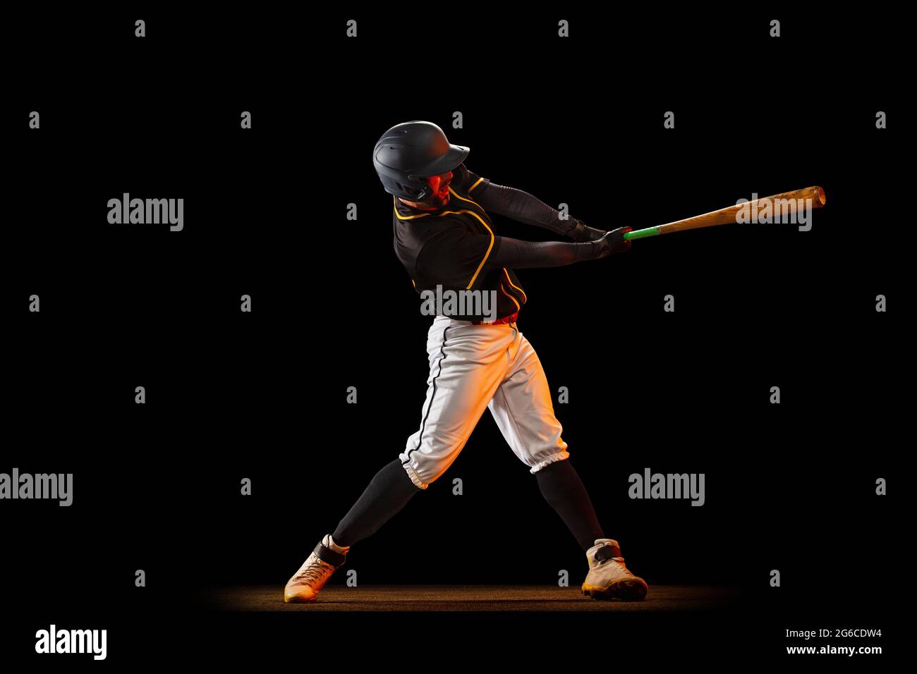 Professional baseball player, pitcher in sports uniform and equipment playing baseball isolated on black studio background in neon light. Team sport Stock Photo