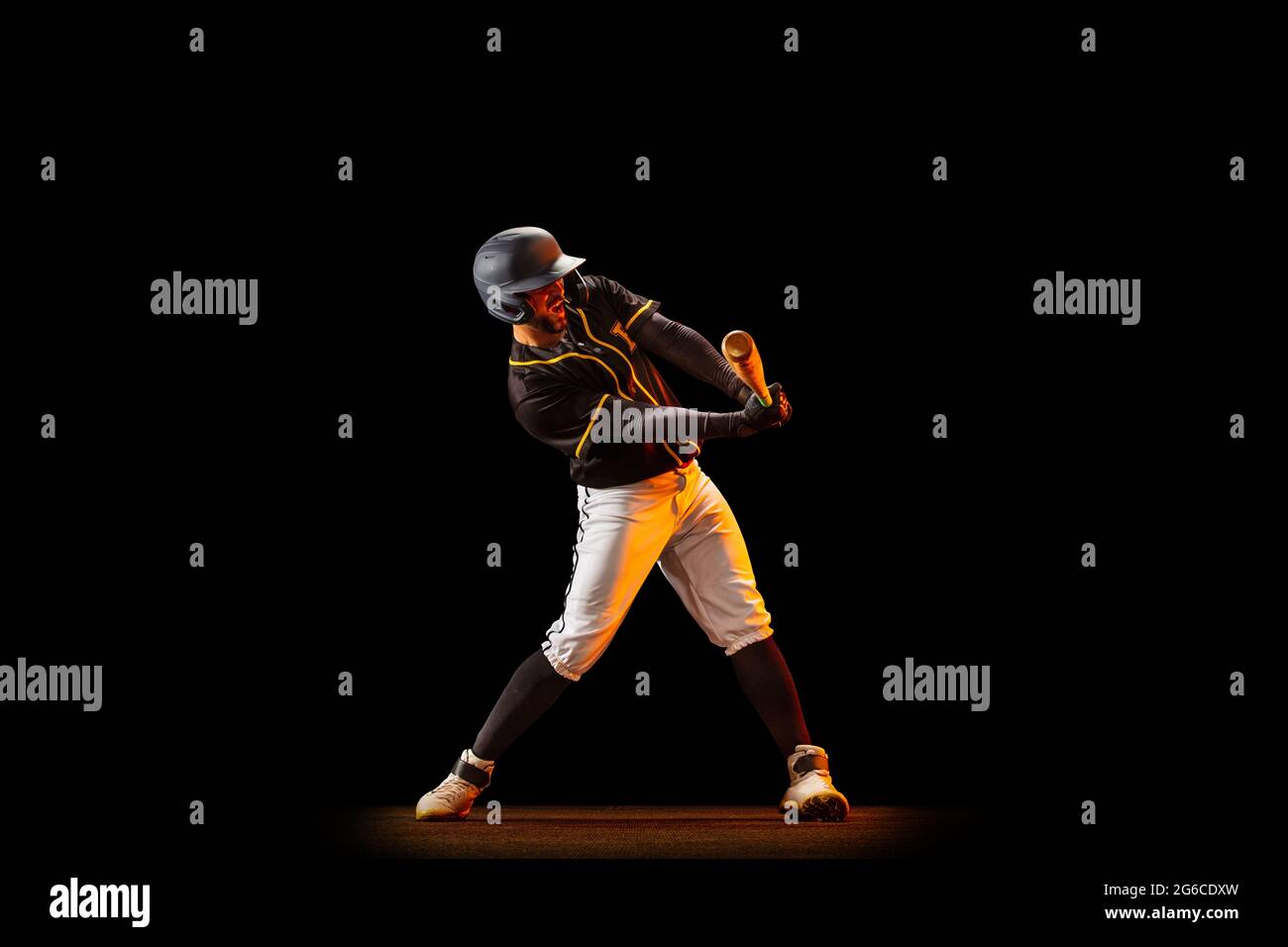 Professional baseball player, pitcher in sports uniform and equipment playing baseball isolated on black studio background in neon light. Team sport Stock Photo