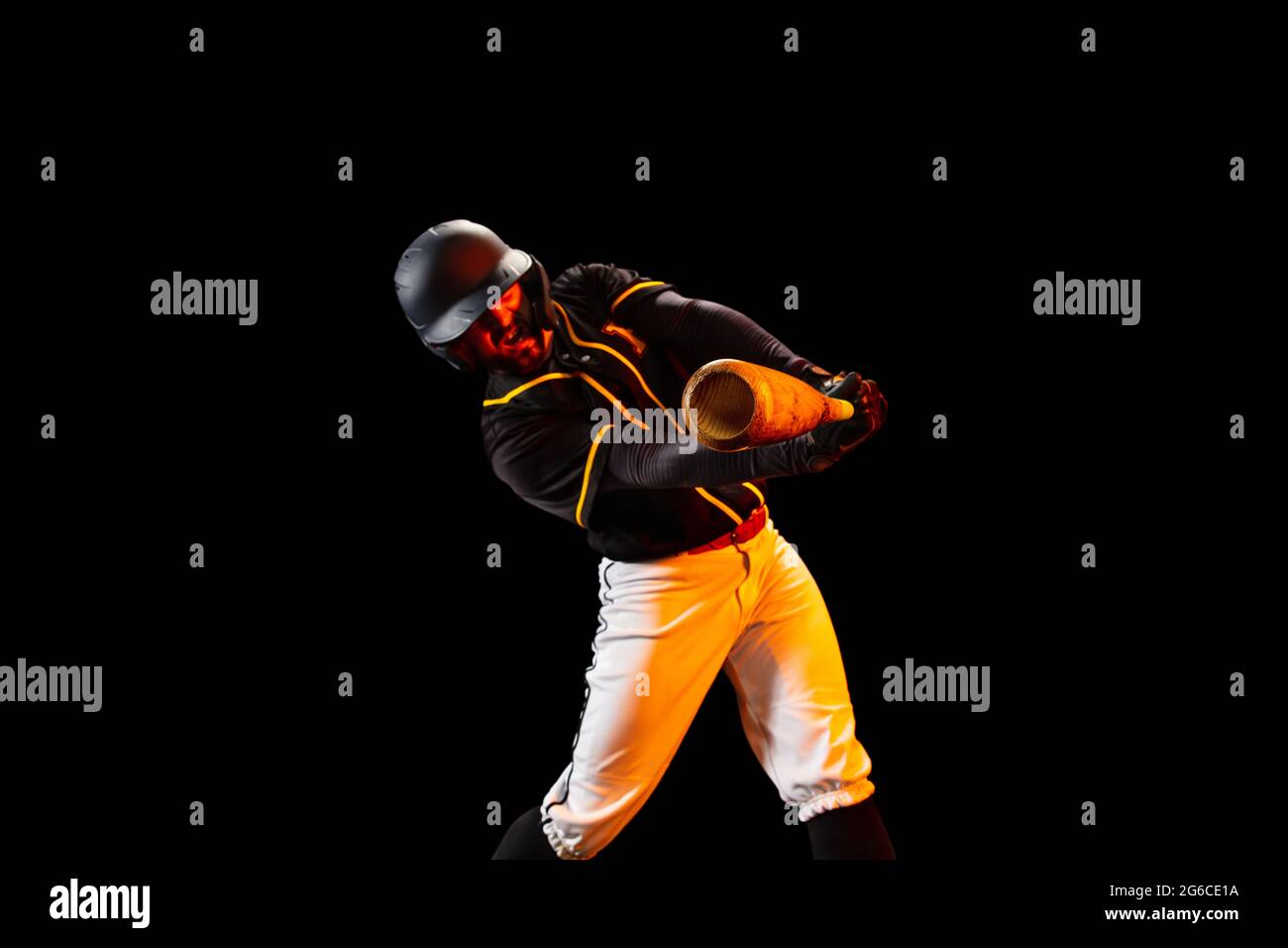 American baseball player, pitcher in sports uniform and equipment playing baseball isolated on black studio background in neon light. Rear view Stock Photo