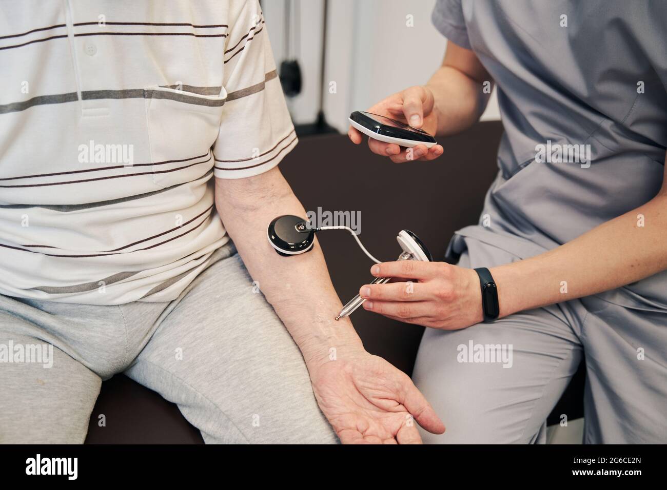 Doctor pressing manual muscle testing device to patient arm Stock Photo